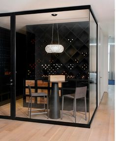 a glass walled dining room with black walls and wooden flooring is seen through the sliding glass doors