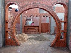 an arch made out of red bricks in the middle of a building under construction with workers working on it