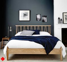 a bed with blue and white sheets in a bedroom next to a fire place on the wall