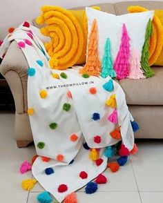 a couch with colorful pillows on it and some tassels around the pillow cover