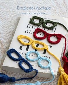 crocheted eyeglasses are on top of a book with tassels