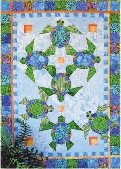 a blue and green quilted wall hanging with turtle designs on the front, along with plants in the back