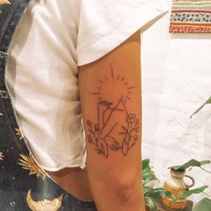 a person with a tattoo on their arm holding a plant and sunburst in the background