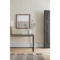 an empty room with a table, chair and framed photograph on the wall next to it