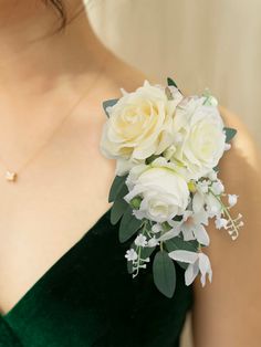 a woman wearing a green dress holding a bouquet of white roses and greenery in her hand