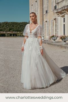 a woman in a wedding dress standing on the street outside an old building with white flowers