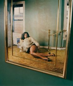 a woman sitting on the floor in front of a mirror