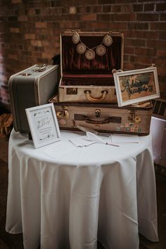 three suitcases are stacked on top of each other at a table with white cloth