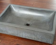 a square sink sitting on top of a wooden floor