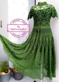 a green dress is on display next to a potted plant