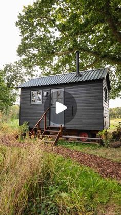 a small black cabin sitting on top of a lush green field