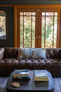 a living room filled with furniture and books on top of a coffee table in front of a window