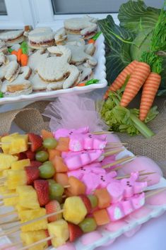 there are many fruits and vegetables on the table with skewers in front of them