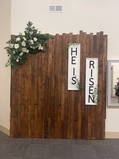 there is a wooden wall with flowers on it and two signs that say helsen