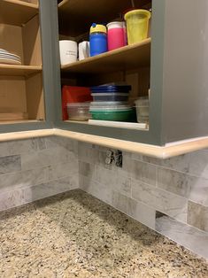 a kitchen with marble counter tops and shelves filled with plastic containers on the bottom shelf