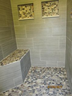 a walk in shower sitting next to a tiled wall and two windows on each side