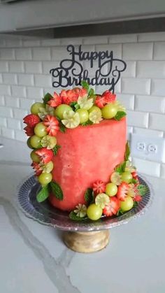 a watermelon and grapes birthday cake on a kitchen counter