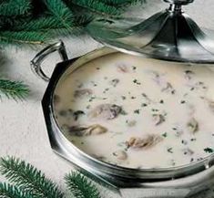 a silver pot filled with soup next to pine branches