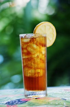 a tall glass filled with iced tea and lemon wedged into the ice cubes