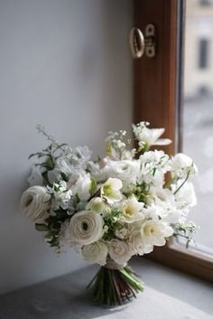 a bouquet of white flowers sitting on top of a window sill next to a door