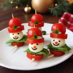 small tomatoes with tomato heads on them are sitting on a plate next to a christmas tree