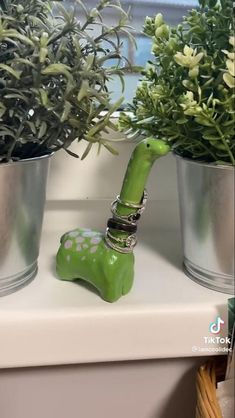 a green elephant figurine sitting on top of a table next to potted plants