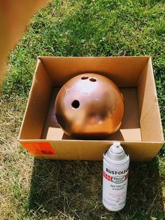 an open box with a ball in it and a spray bottle on the ground next to it