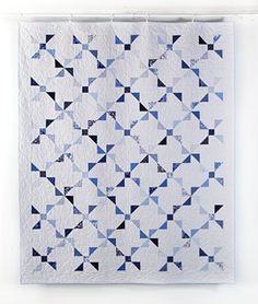 a blue and white quilt hanging on a wall