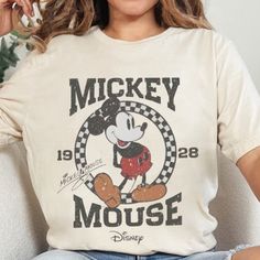 a woman sitting on top of a couch wearing a mickey mouse t - shirt