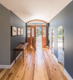 an entryway with wooden floors and blue walls, along with a wood door that leads to another room