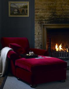 a red chair sitting in front of a fire place with a blanket on it's back