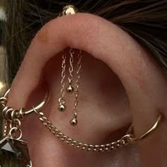 a close up of a person's ear with gold chains attached to the ears