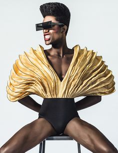 a woman sitting on top of a chair wearing a gold dress and blindfolds