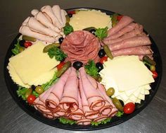 an assortment of meats and cheeses arranged in a circle on a platter