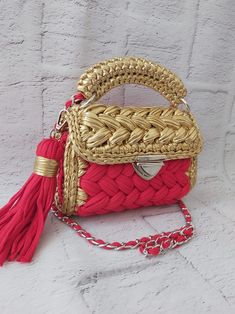 a red and gold handbag with a tasseled handle on a white background