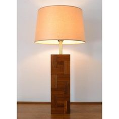 a lamp that is sitting on top of a wooden block with a white shade over it