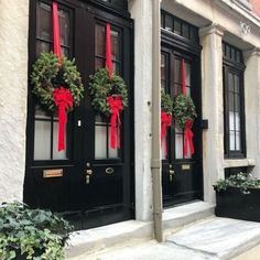 two black doors decorated with wreaths and red ribbons on the front of a building