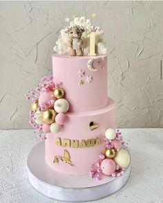 a pink cake with gold decorations and teddy bears on top is shown in front of a white background