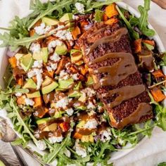 a salad with meat, avocado, and feta cheese on the side