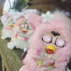 three pink stuffed animals sitting on top of a wooden bench next to eachother