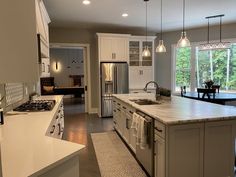 a large kitchen with an island in the middle and lots of lights hanging from the ceiling