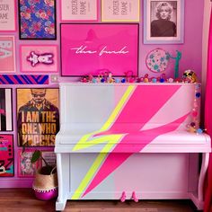 a pink and yellow painted piano in a room with pictures on the wall