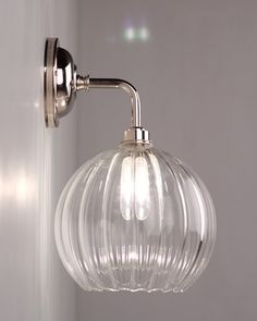 a clear glass globe light hanging from the side of a wall