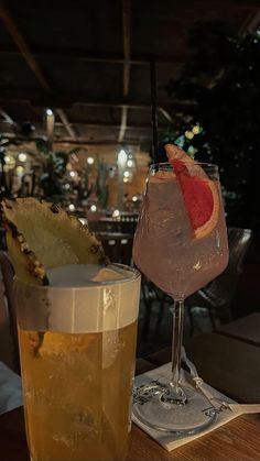 two glasses filled with drinks sitting on top of a wooden table next to each other