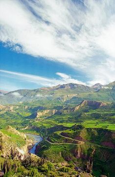 the mountains are covered in green grass and trees, with a river running between them