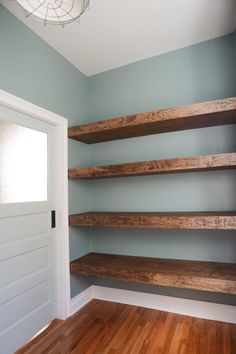 empty shelves in the corner of a room with wood flooring and blue paint on the walls