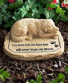 a stone statue of a dog laying on it's side in front of some flowers