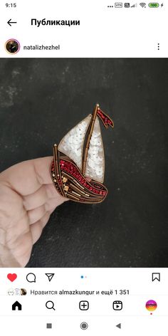 someone is holding a brooch with a sailboat on it