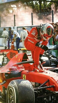 a man standing on top of a red race car