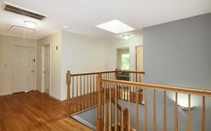 an empty living room with hard wood flooring and white walls on either side of the stairs